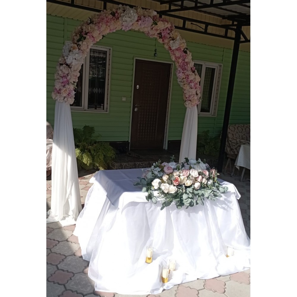 Арка с цветами и тканью и стол с оформлением